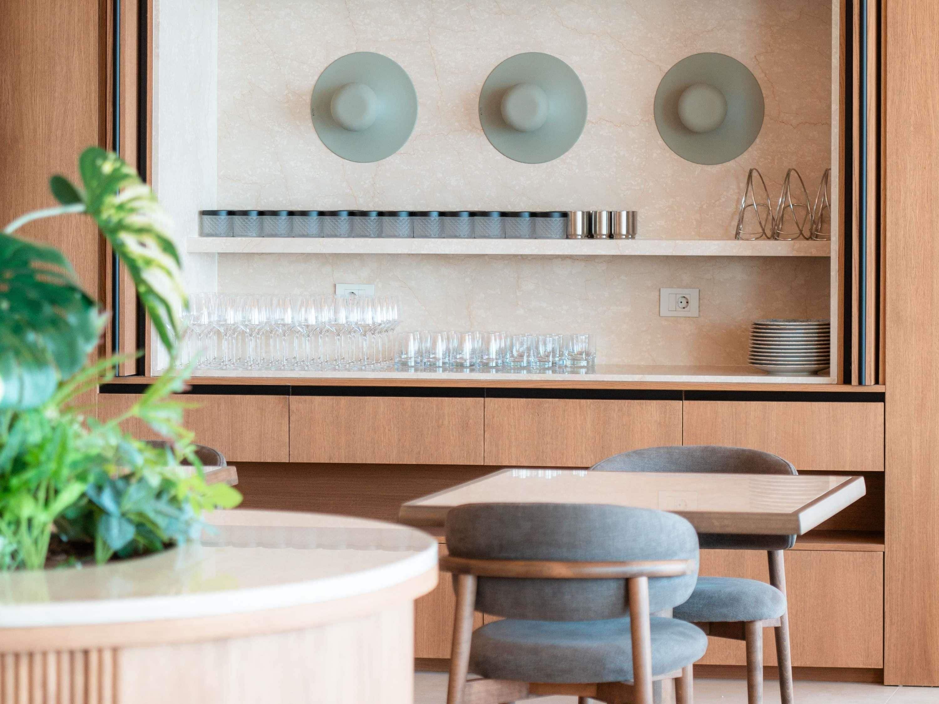 A modern kitchen with a wooden countertop, a dining table with chairs, and a wall-mounted light fixture.