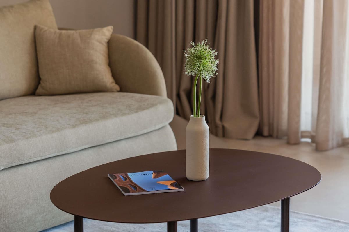 Ein Wohnzimmer mit einer Couch, einem Couchtisch, einer Vase mit Blumen und einer Zeitschrift.