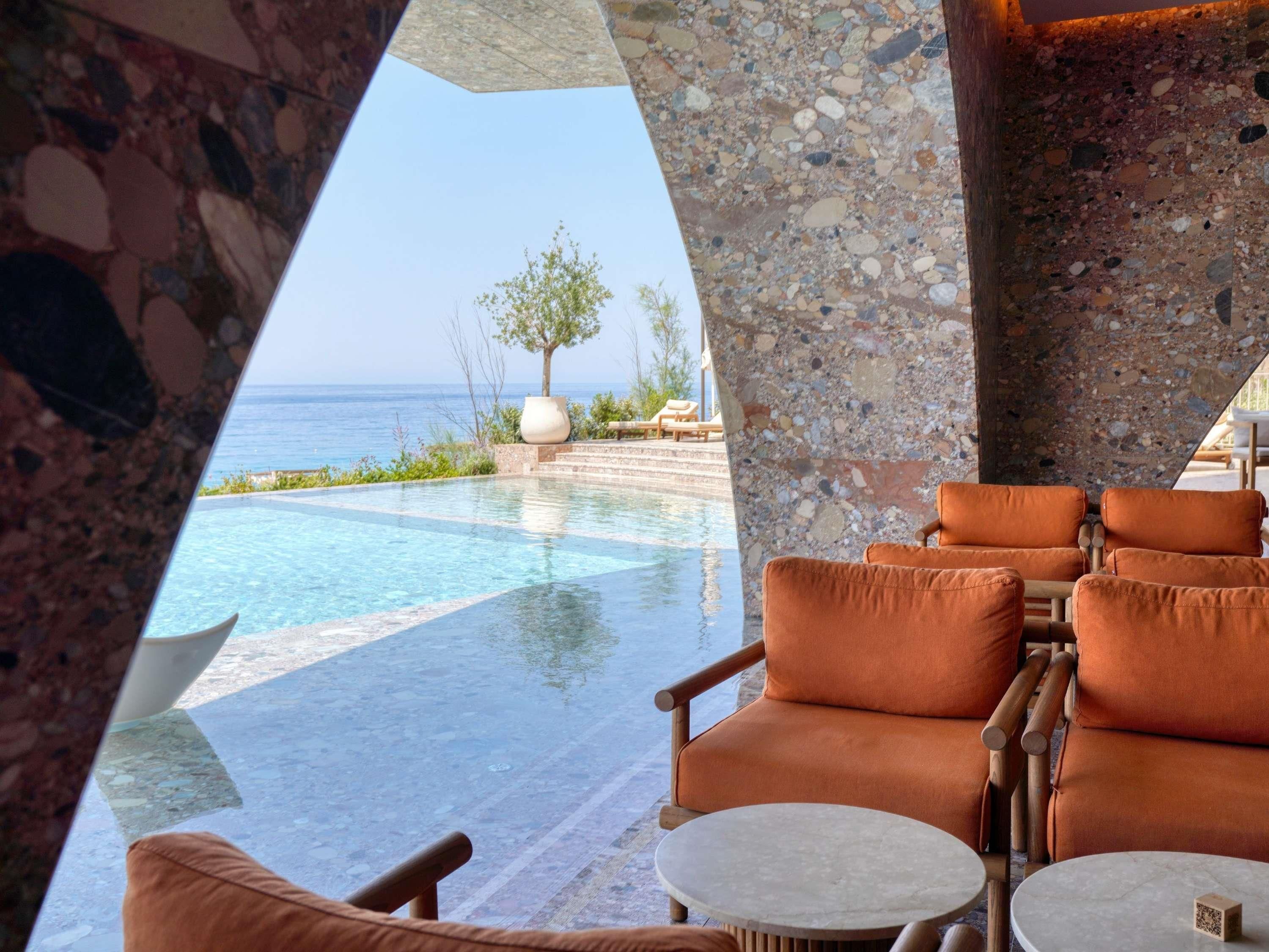 A poolside area with lounge chairs and a view of the ocean.