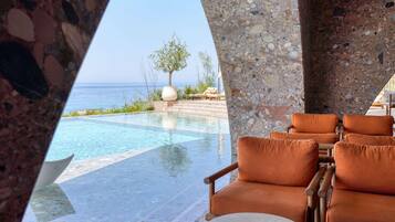 A poolside area with lounge chairs and a view of the ocean.