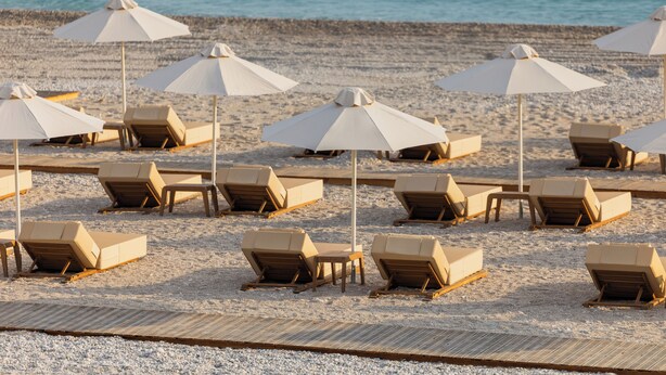 A beach with multiple sun loungers and umbrellas arranged in rows. - Green Coast Hotel Mgallery Collection (Himare)