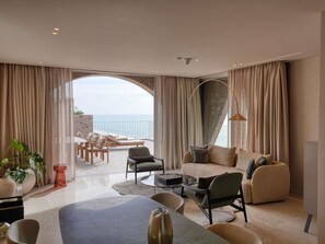 A spacious living area with a view of the sea, a balcony with outdoor seating, and a modern interior design.