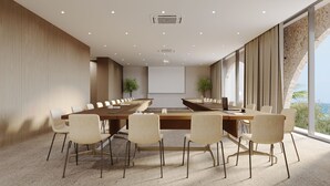 A modern conference room with a long table, white chairs, and a projector screen. - Green Coast Hotel Mgallery Collection (Himare)