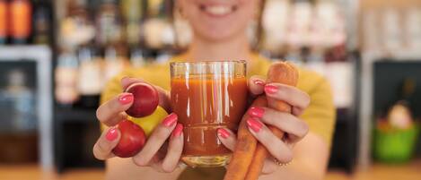 Una persona sosteniendo un vaso de jugo de naranja y dos zanahorias.
