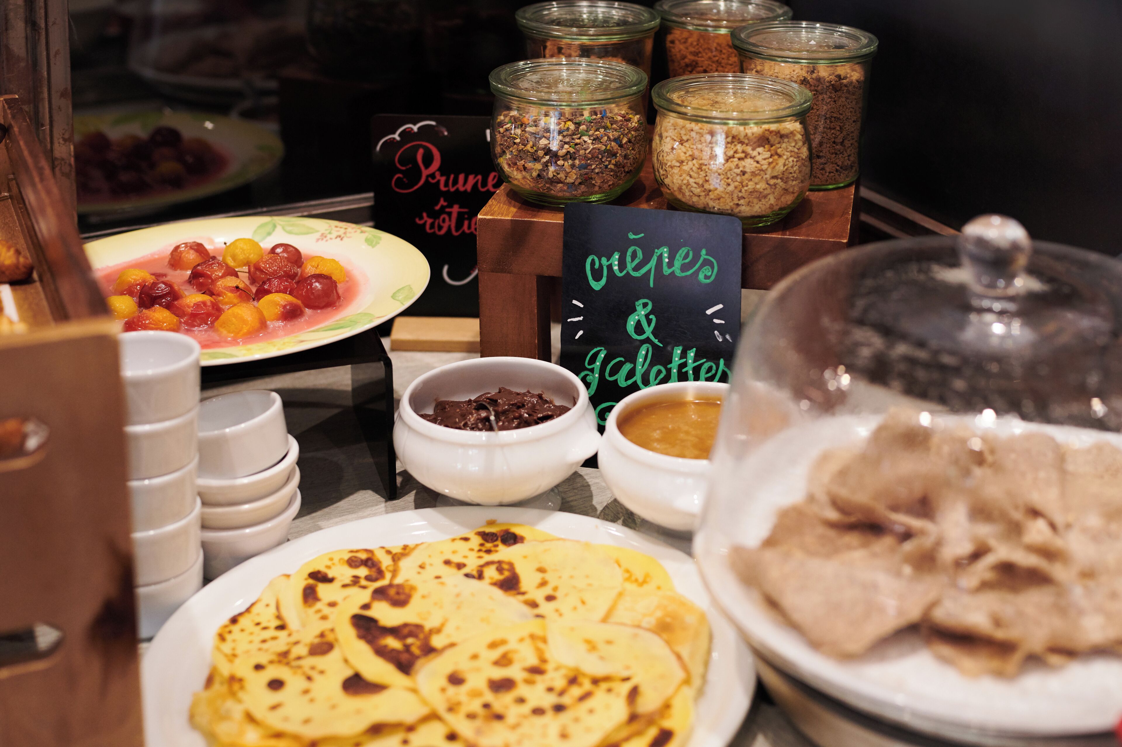 Un buffet proposant une variété de plats, notamment des crêpes, des galettes, ainsi qu’un assortiment de sauces et d’accompagnements.