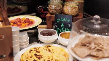 Un buffet proposant une variété de plats, notamment des crêpes, des galettes, ainsi qu’un assortiment de sauces et d’accompagnements.