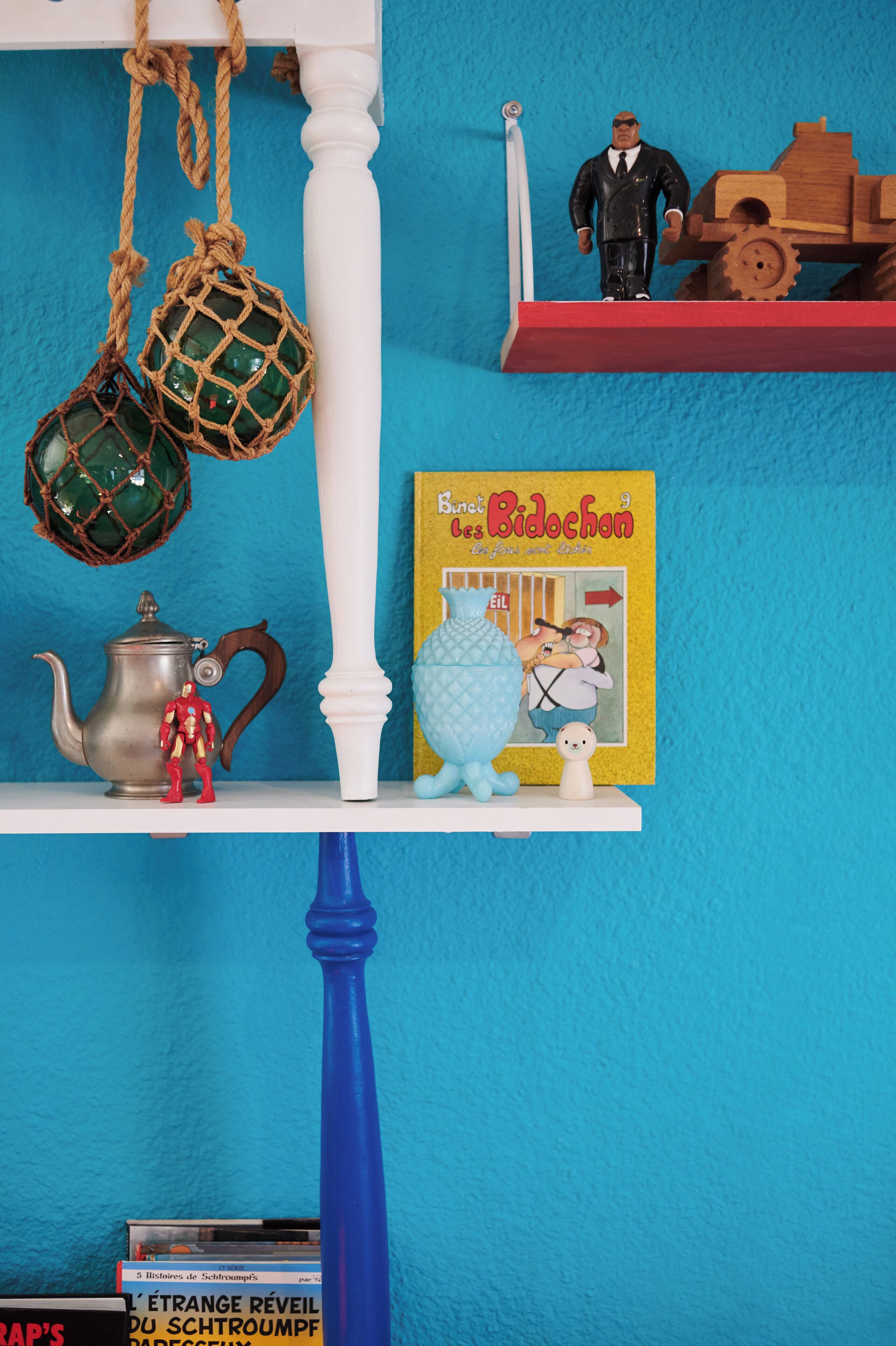 A shelf with various items including a book, figurines, and a teapot.