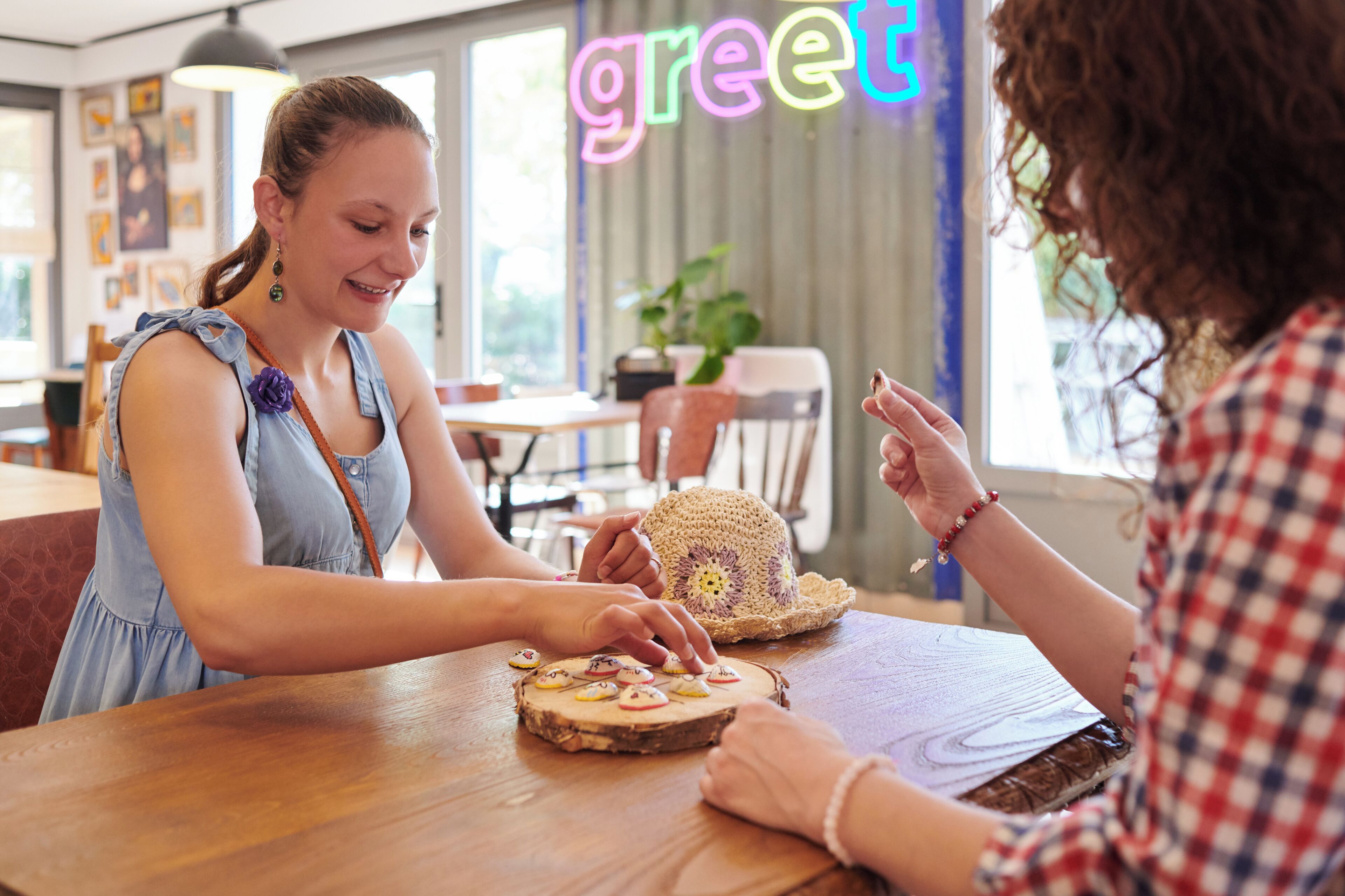 Two people sitting at a wooden table with a hat and cookies.