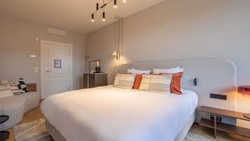 A modern hotel room with a large bed, bedside tables, a desk, and a wardrobe.