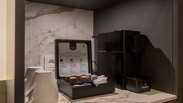 A minibar with a coffee maker, a coffee menu, and a coffee cup.