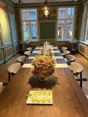 Une salle de conférence avec une longue table, des chaises, un arrangement floral en guise de décoration centrale et un présentoir à menus.