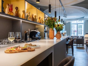Zona de bar con mostrador que exhibe vasos, una máquina de café y una selección de alimentos y bebidas.