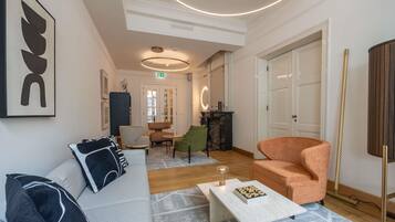 A modern hotel lobby with a sofa, armchairs, a coffee table, and a fireplace.