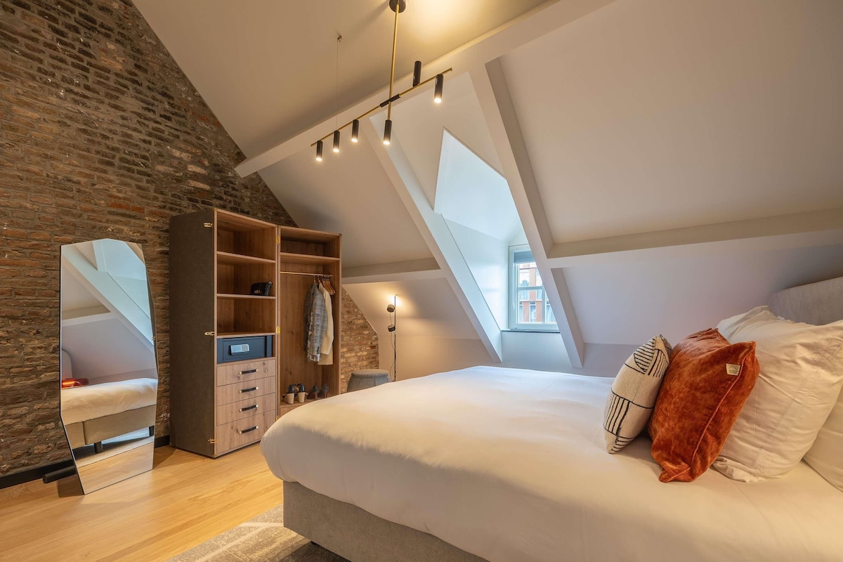 Une chambre avec un plafond de style industriel, un grand lit, une armoire et un miroir.