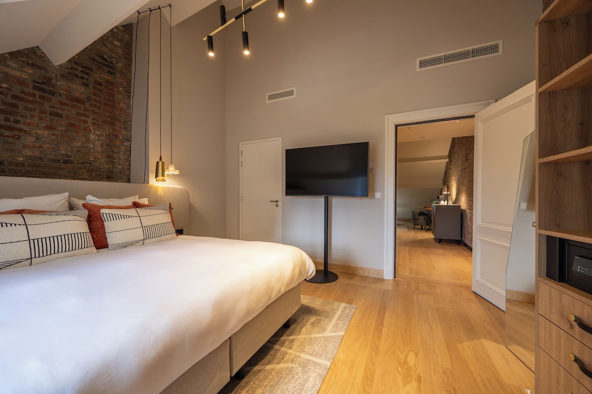 Une chambre avec un lit, une télévision, un mur en briques et un plancher en bois.