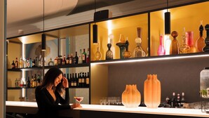 Un espace bar avec des étagères remplies de bouteilles, un comptoir et une personne assise.