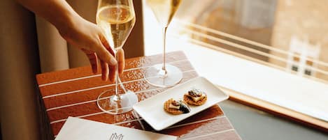 A table with two wine glasses, a plate with food, and a menu on a wooden box.