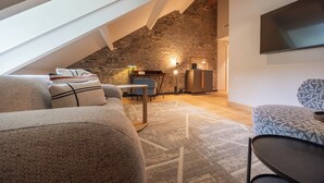 Une pièce de style « loft » avec un plafond en pente, un mur en briques apparentes et un téléviseur à écran plat fixé au mur.
