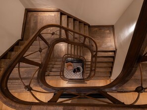 A spiral staircase with a central open area, wooden walls, and a metal railing. - Hotel Maison Maastricht Centrum - Handwritten Collection (Maastricht)