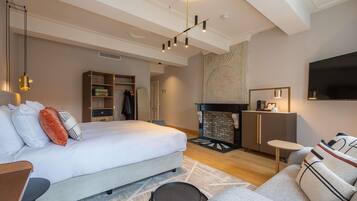 Una habitación de hotel moderna con una cama grande, chimenea, televisor y un espacio para sentarse.