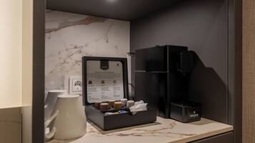 Een minibar met een koffiezetapparaat, een keuze koffiekapsules en een waterdispenser.