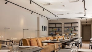 A modern dining area with tables, chairs, and a sofa.