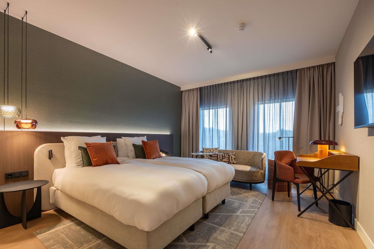 Een moderne hotelkamer met een groot bed, een bureau, een stoel en een bank.