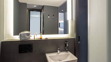 A modern bathroom with a large mirror, a sink, and a towel rack.