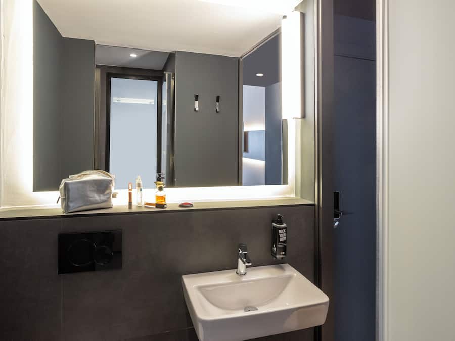 A modern bathroom with a large mirror, a sink, and a towel rack.