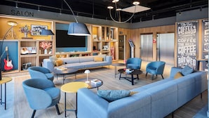 A modern lounge area with a sofa, armchairs, and a coffee station. - ibis Madrid Norte Las Tablas (Madrid)