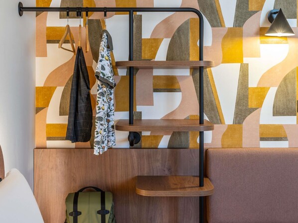 A wall-mounted shelf with hanging clothes and a backpack. - Ibis Styles Marseille Palais Des Congrès Vélodrome (Marseille)