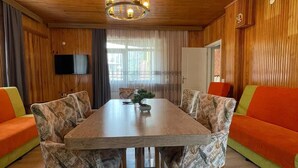 A wooden-paneled room with a dining table, chairs, and a television on the wall. - EL'A APART HOTEL (Camlihemsin)