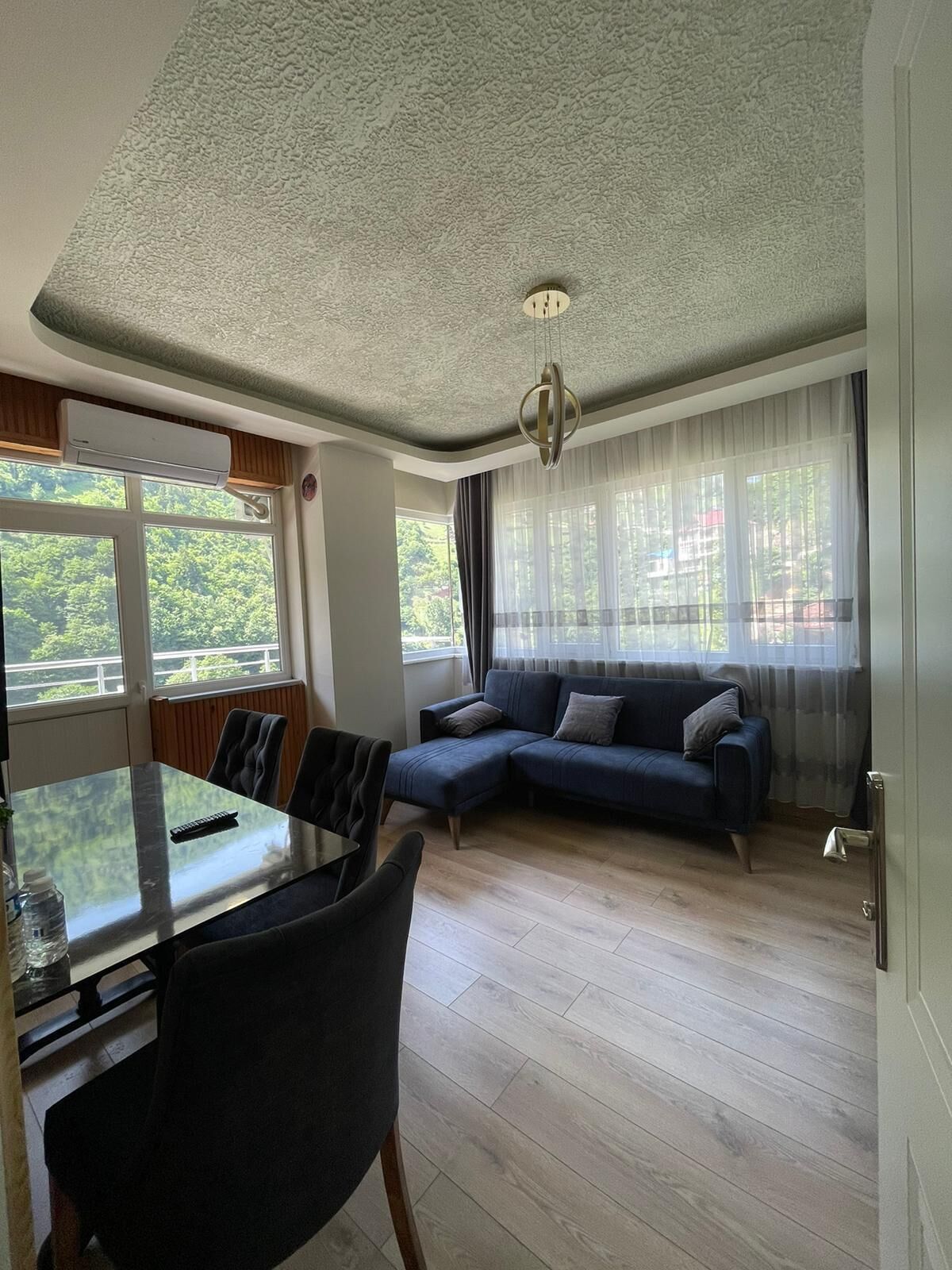 A modern living room with a dining area, a sofa, and a ceiling light fixture.