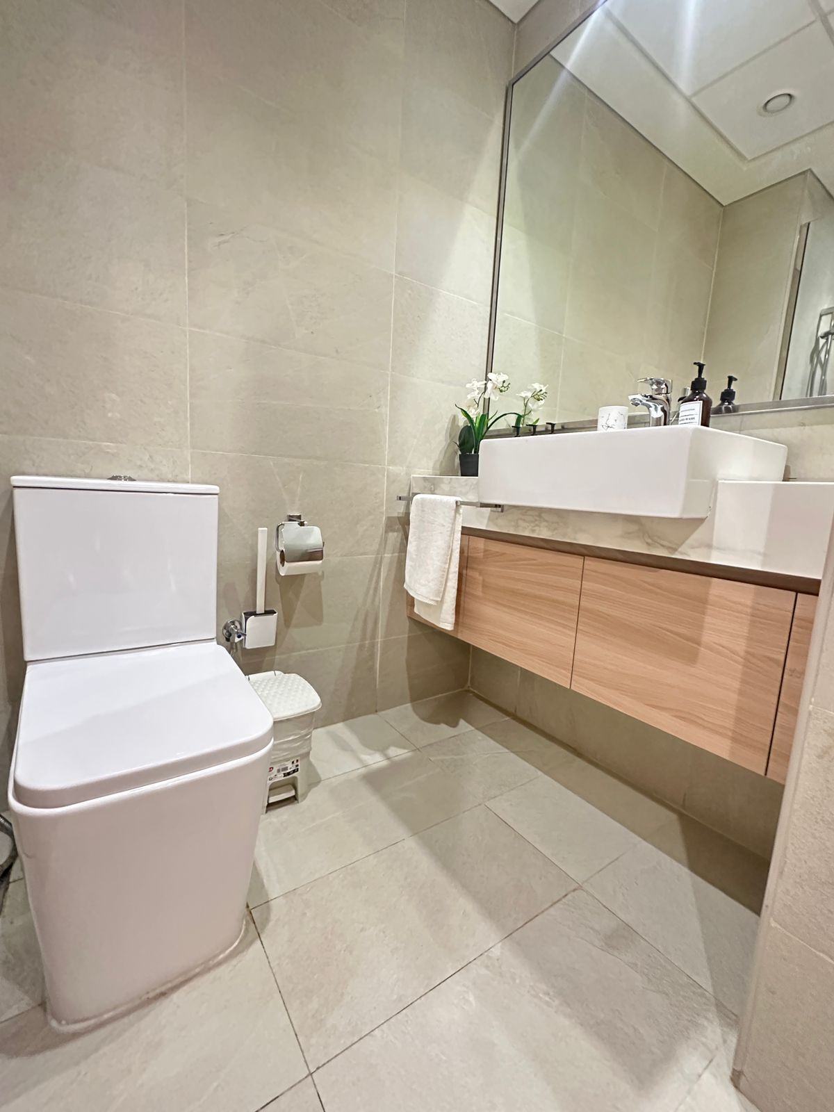 A modern bathroom with a toilet, sink, and mirror.