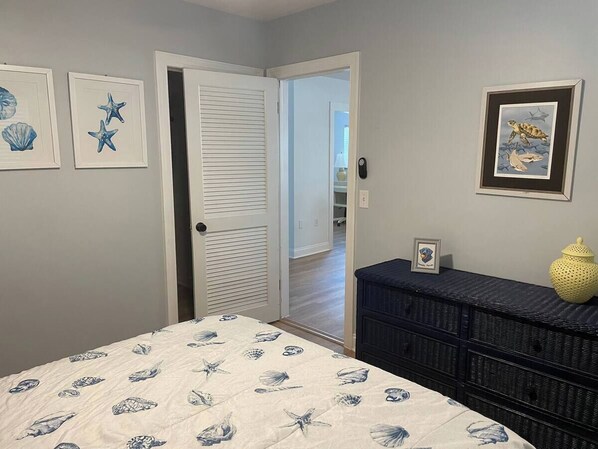 A bedroom with a bed, a dresser, and a door leading to another room. - The blue jays nest; a 3-bedroom house with WiFi, AC in marvelous Dunedin (Dunedin)
