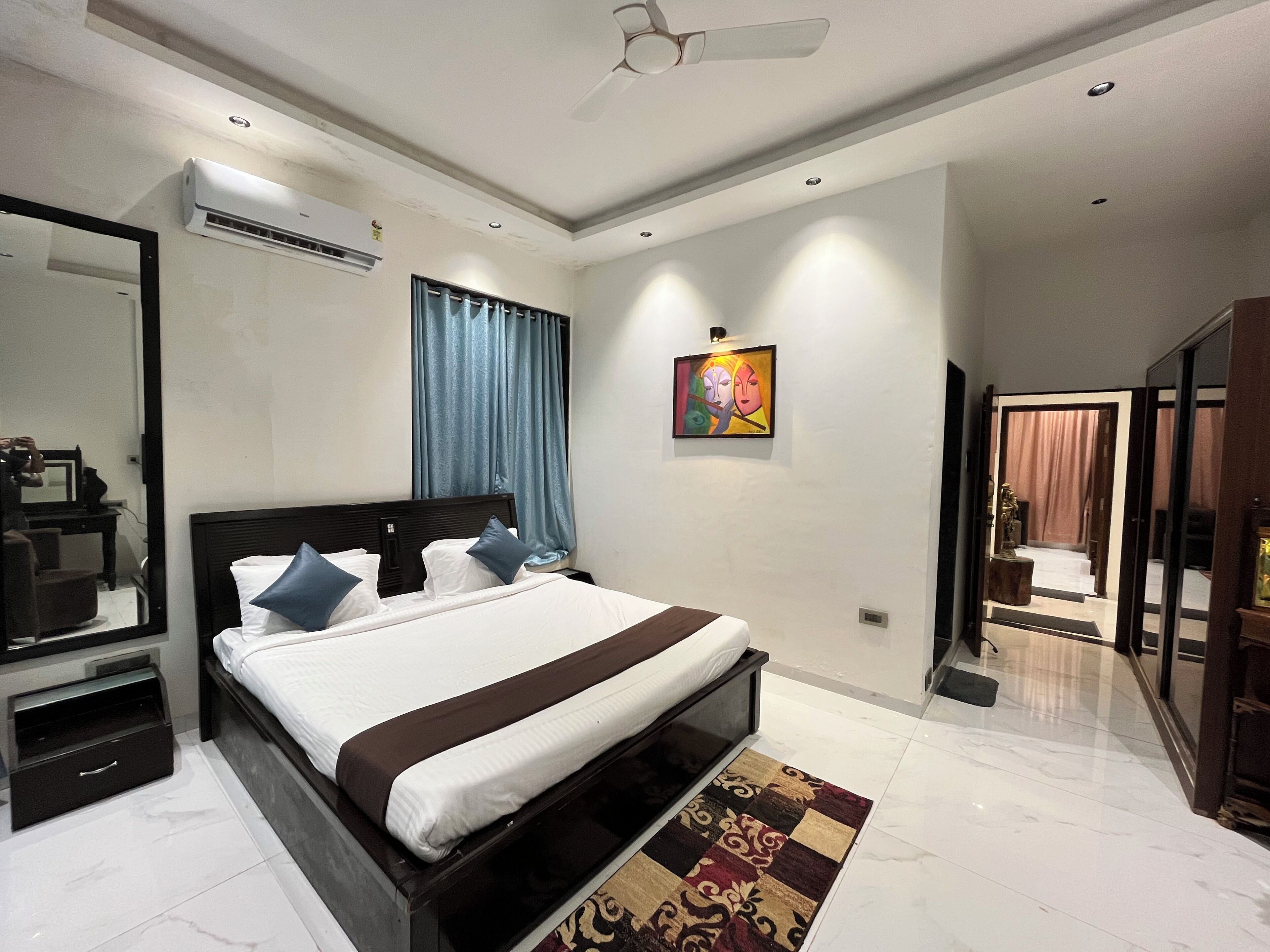 A modern bedroom with a large bed, a desk, and a mirror.