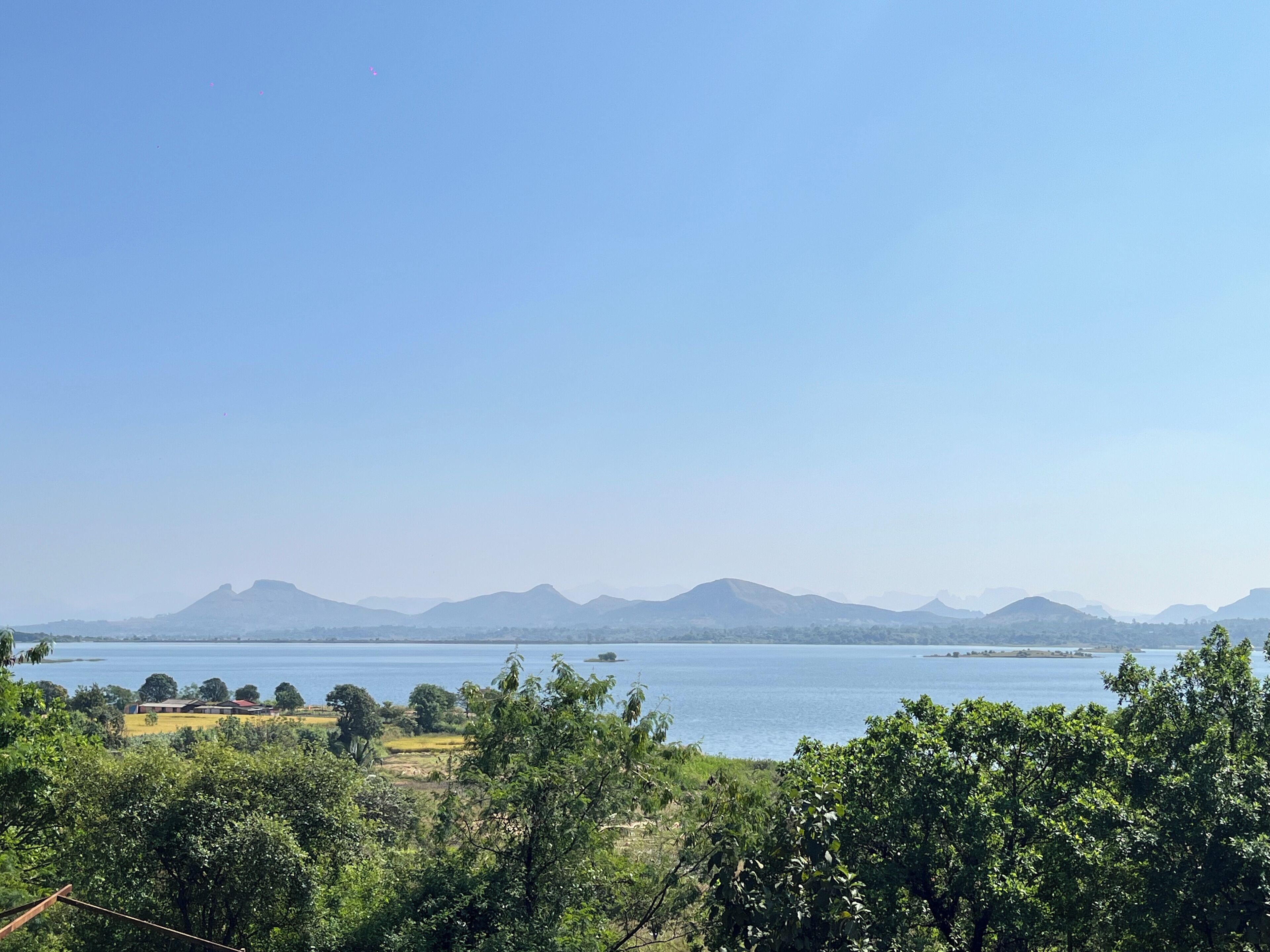 Panoramica di un paesaggio costiero con montagne sullo sfondo e una distesa d'acqua in primo piano.