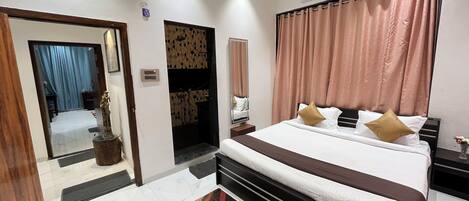 Una habitación de hotel moderna con una cama grande, un baño con ducha y una pequeña mesa con un florero.