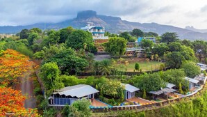 A resort with multiple buildings surrounded by lush greenery and a mountain backdrop. - Astoria Lagoon Resort (Igatpuri)