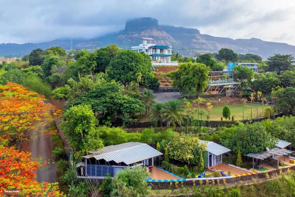 A resort with multiple buildings surrounded by lush greenery and a mountain backdrop.