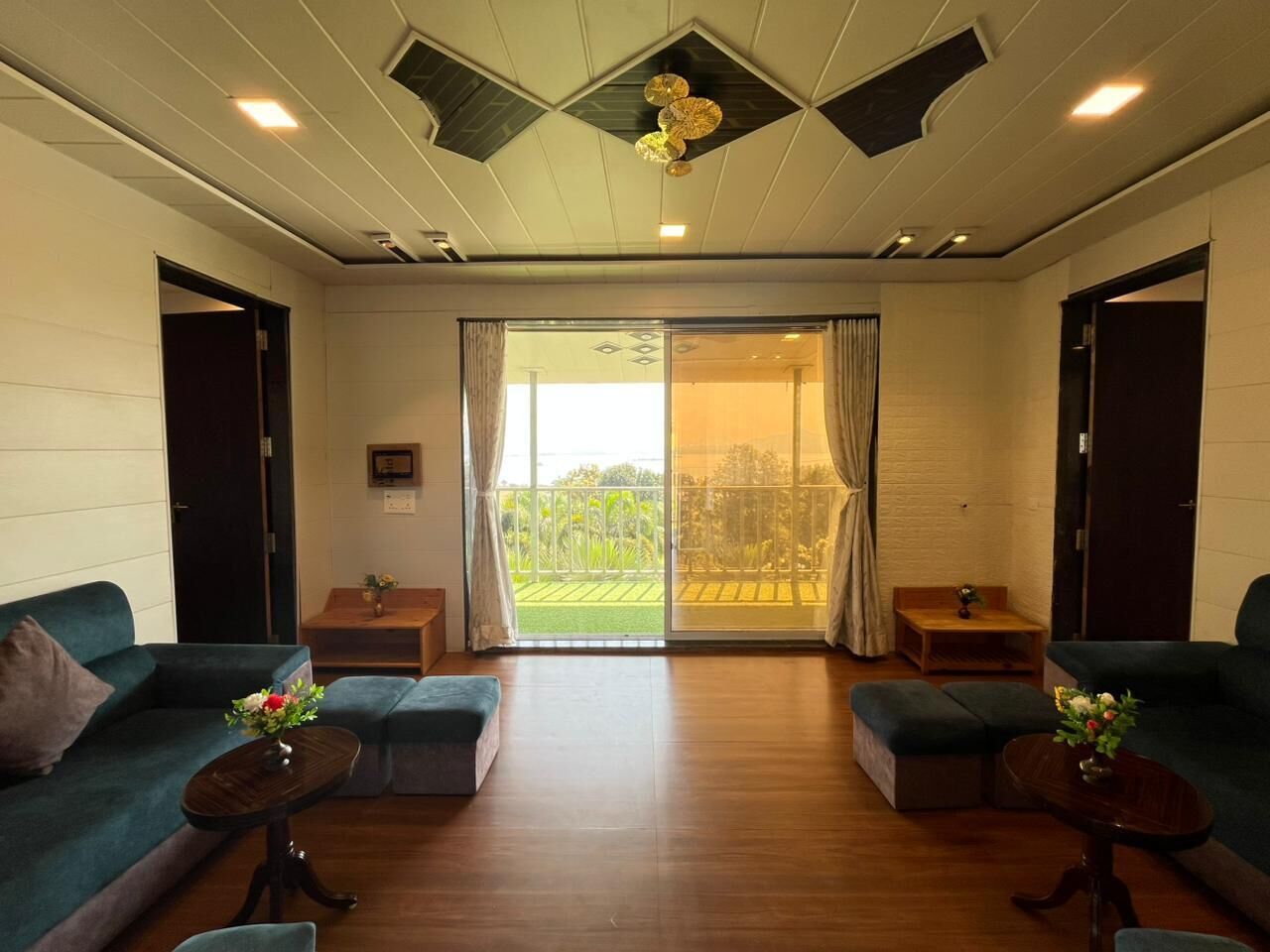 A spacious living room with a large sliding glass door leading to a balcony, two sofas, a coffee table, and a small side table.