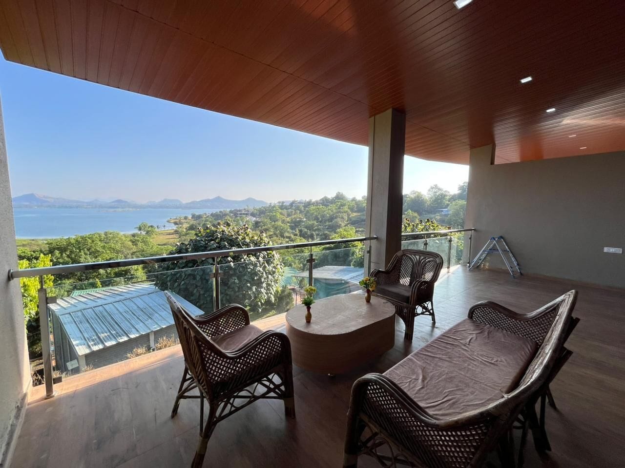 A balcony with wicker furniture, a round table, and a view of a mountainous landscape.