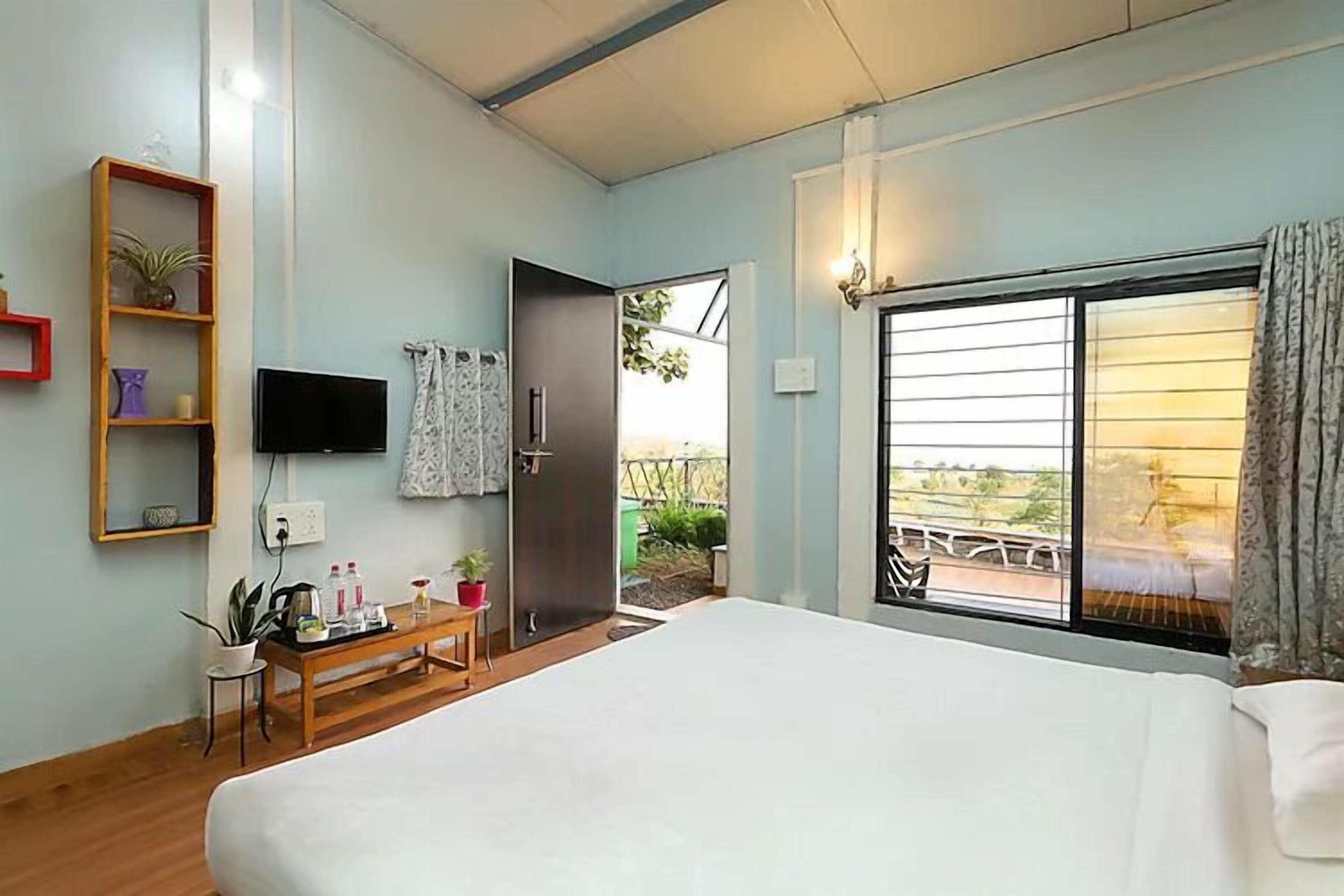 A bedroom with a bed, a TV, a desk, and a window with a view of a bridge.