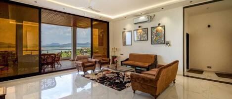 A spacious living room with a large glass door leading to a balcony, a sofa, a coffee table, and a rug.