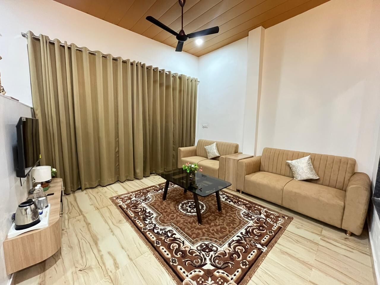 Un salon avec un canapé, une table basse, un téléviseur et un ventilateur de plafond.