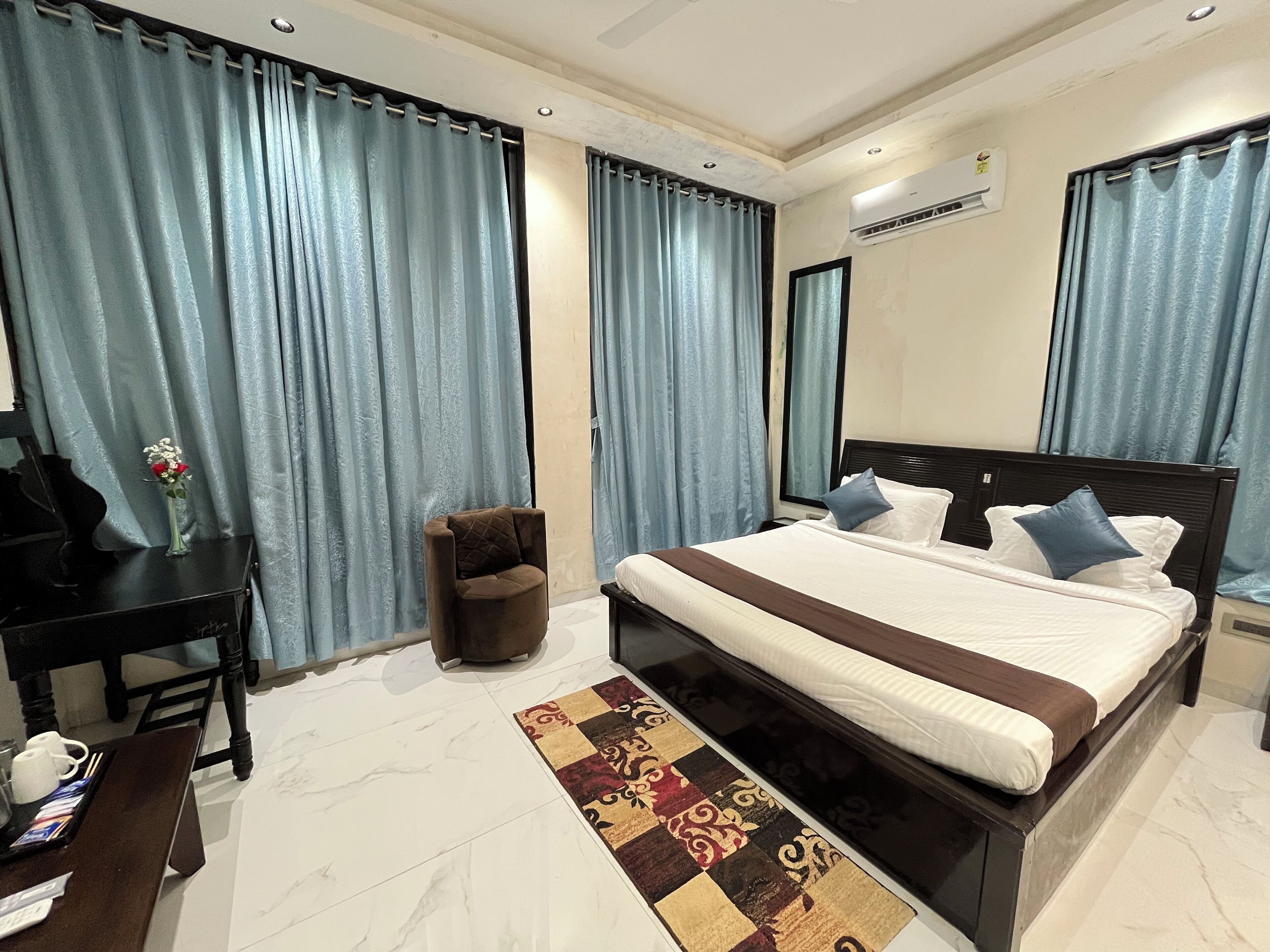 Une chambre d’hôtel moderne avec un grand lit, un petit bureau, une chaise et un tapis décoratif.