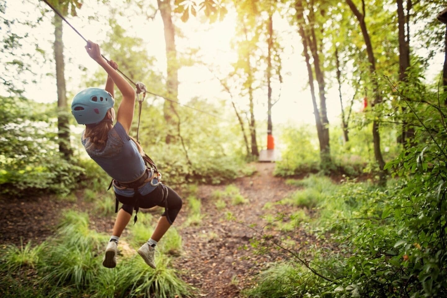 A person zip-lining through a forested area.
