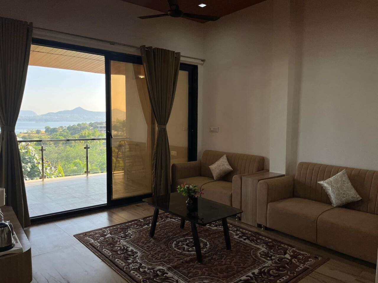 A living room with a sofa, a coffee table, and a view of a balcony with curtains.
