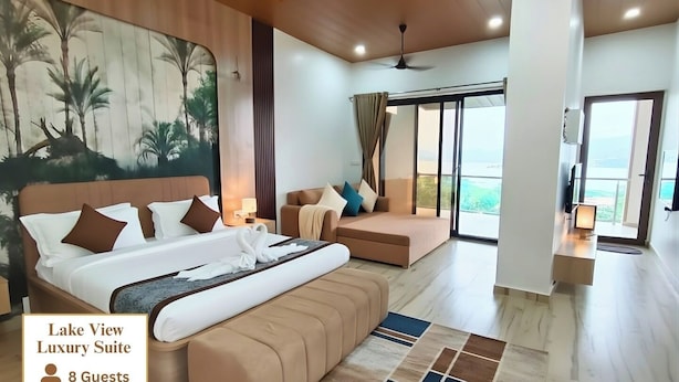 A spacious room with a large bed, a sofa, and a view of the outdoors. - Astoria Lagoon Resort (Igatpuri)