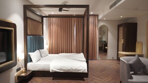 A modern hotel room with a large bed, a desk, a chair, and a ceiling fan.